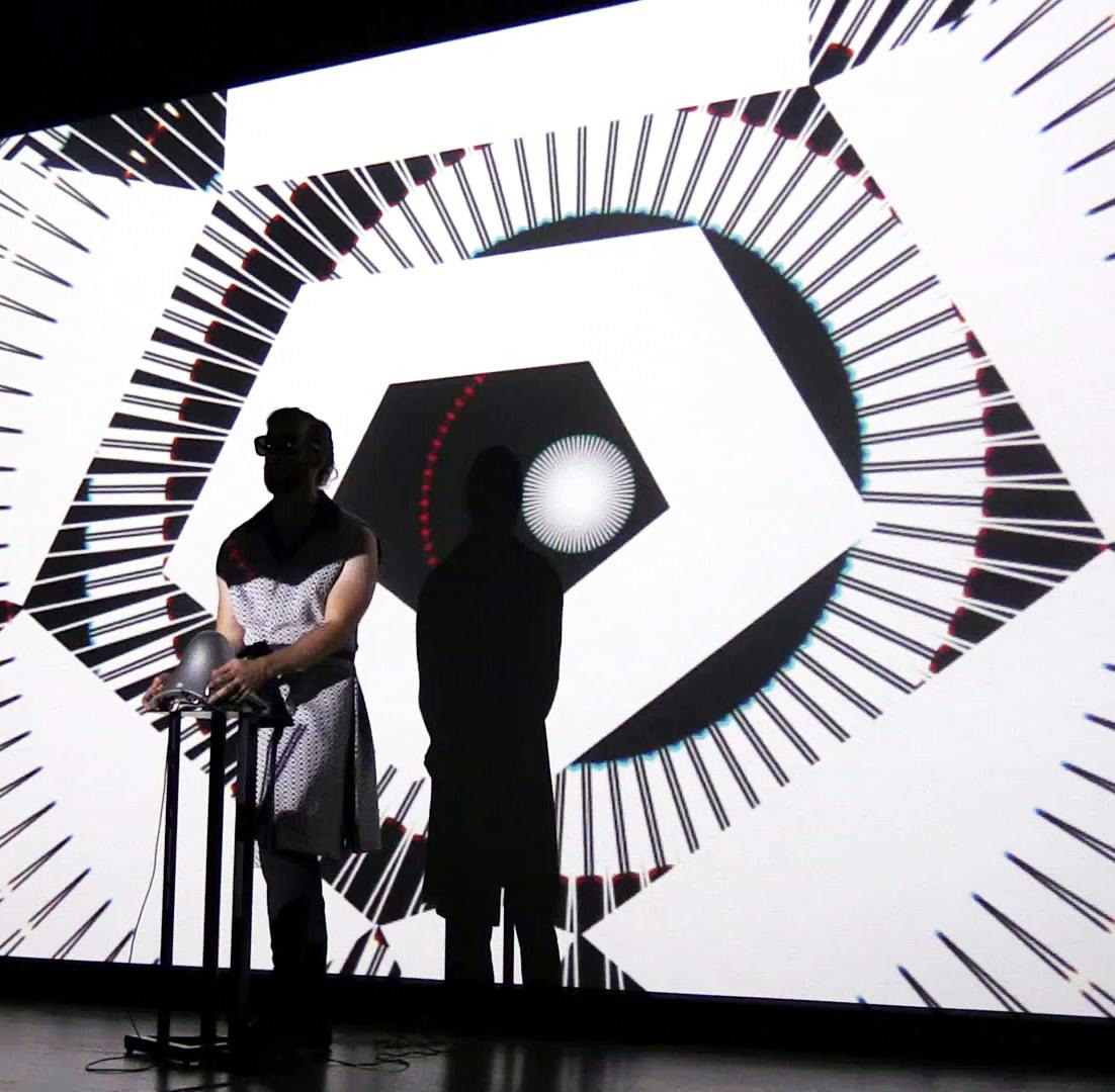 Performer with synthesizer standing in black and white projections