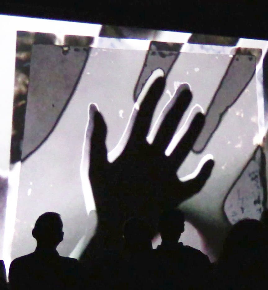 Grey and white projection interrupted by a large hand shadow